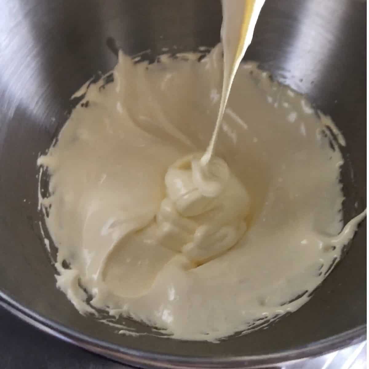 Fluffy pale glossy pate a bombe holding ribbons after whipping for 10 to 12 minutes ready for mascarpone for tiramisu cream.