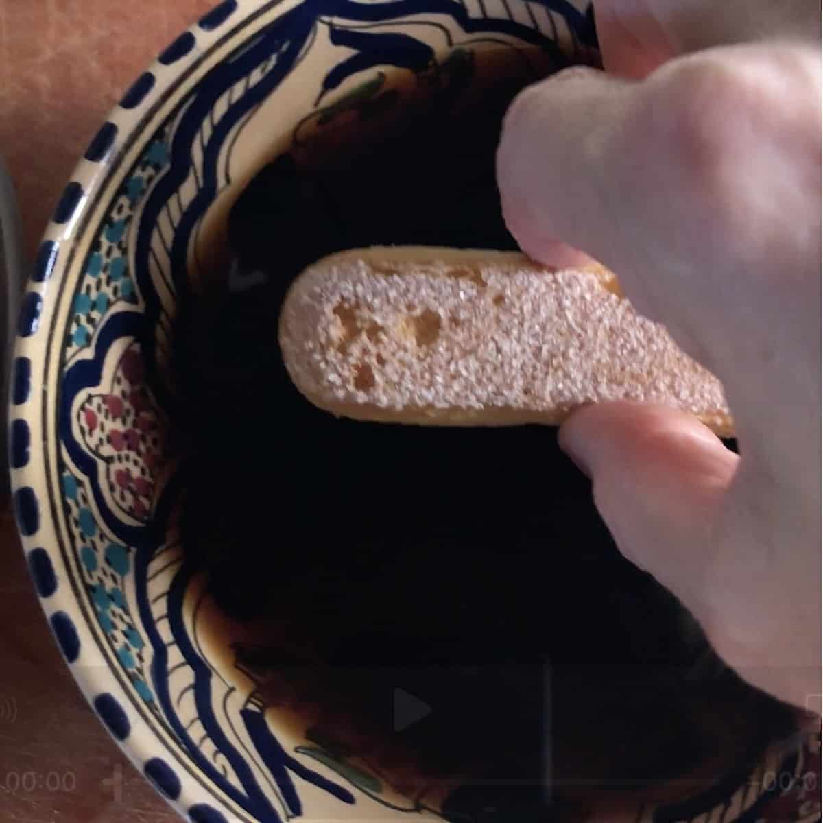 Dipping ladyfingers quickly into espresso for the perfect soak, never soggy for tiramisu.