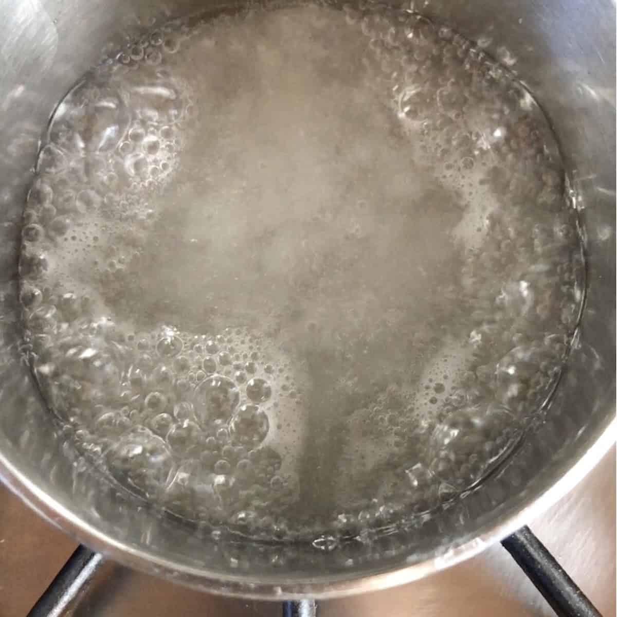 Stage two of cooking sugar syrup with large bubbles forming around the perimeter of the pot for pate a bombe tiramisu method.