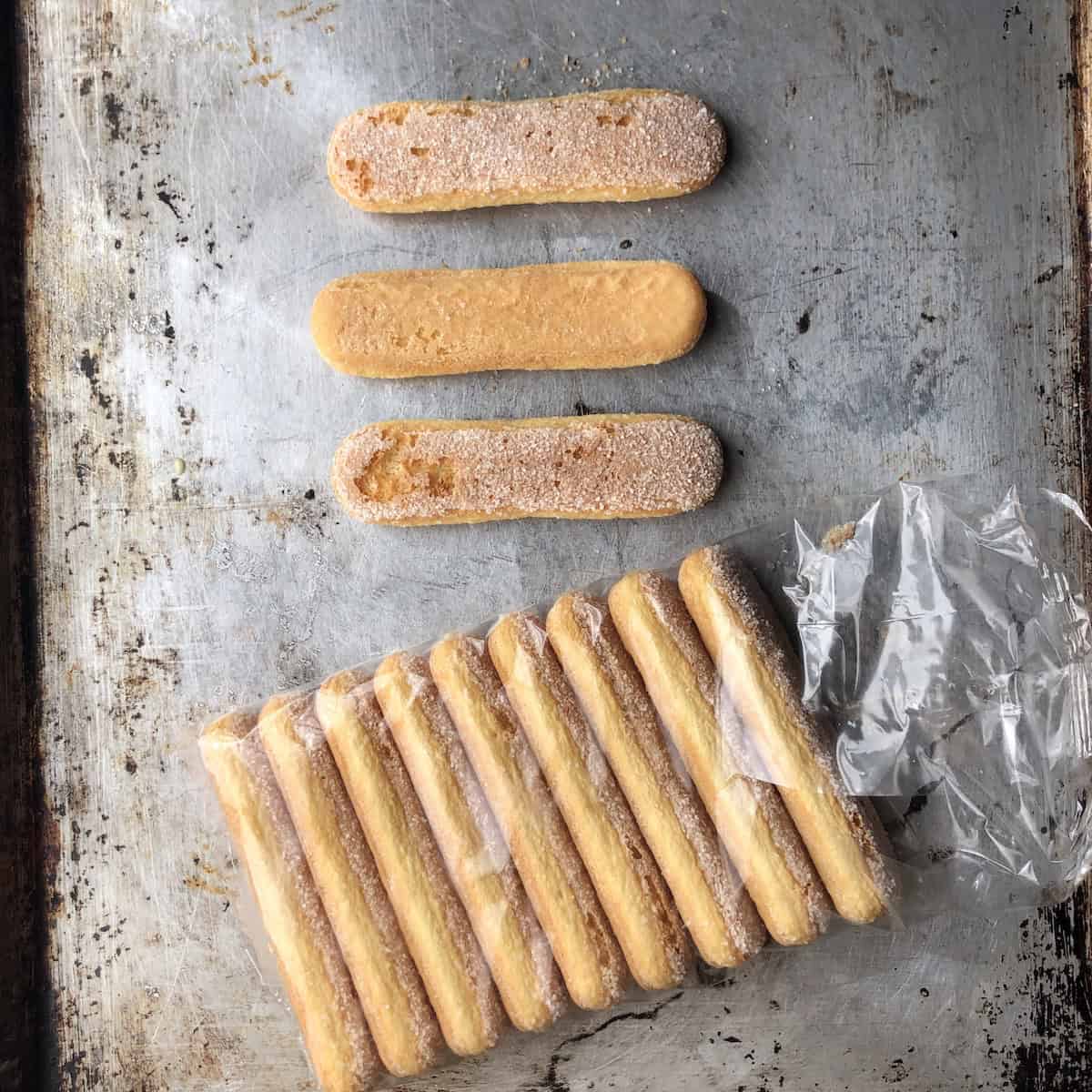 Open package of Vicenzi savoiardi with three ladyfingers showing sugar coated top, bottom side, and remaining ladyfingers in package for tiramisu.
