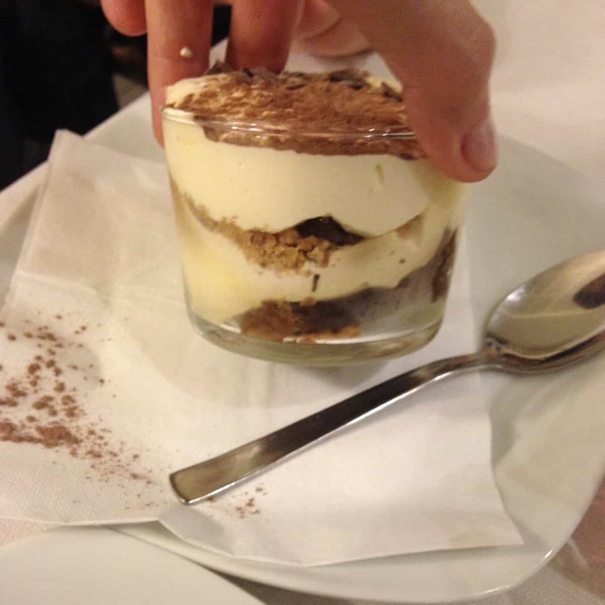 Sideview of our individual mini tiramisu layered in a glass serving cup with super creamy tiramisu filling, dark chocolate garnish and cocoa powder, easy tiramisu recipe.