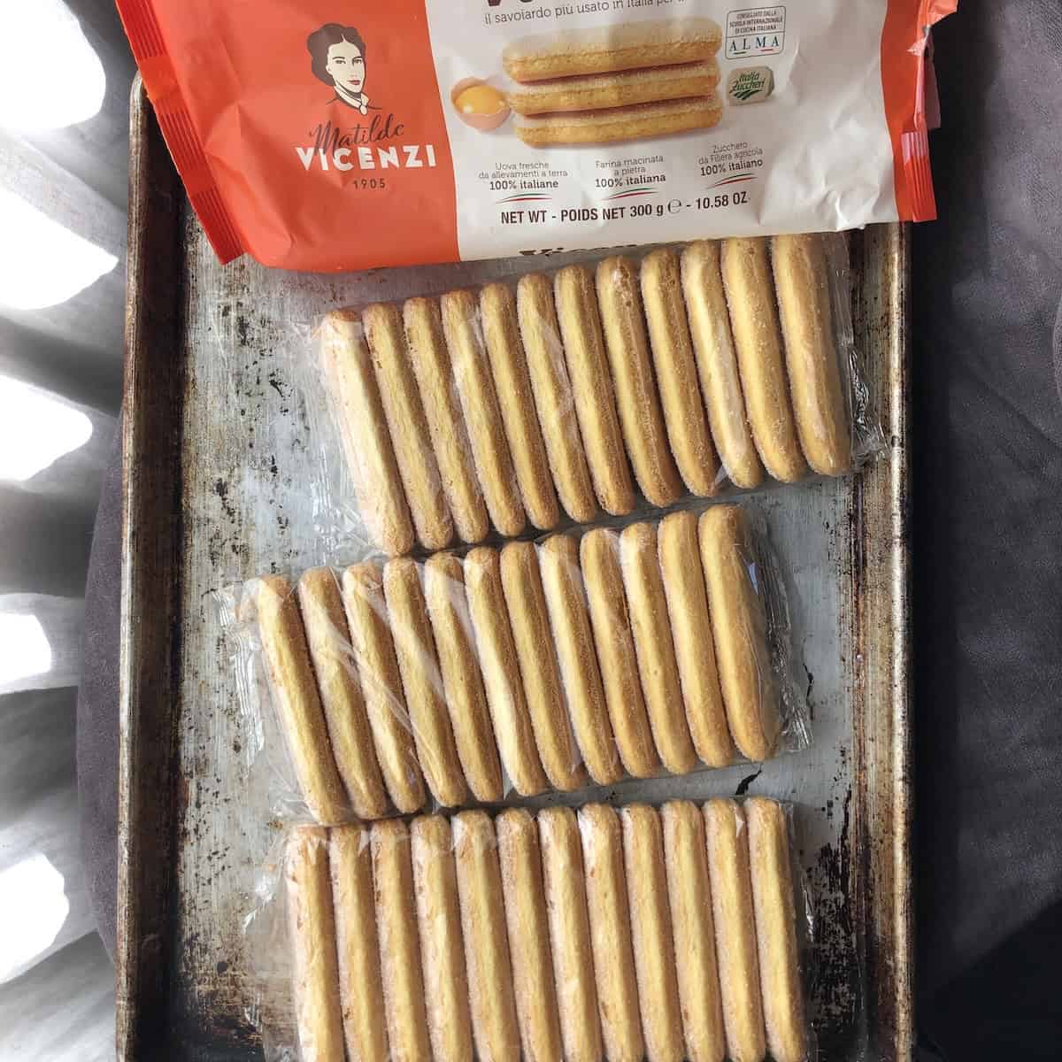 Vicenzovo savoiardi package opened to show three sealed internal packs of ladyfingers on a tray, key ingredient for tiramisu.
