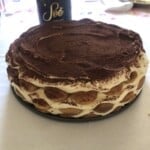Tiramisu in a 9-inch springform cake pan with three layers and ladyfingers arranged around the perimeter showing rounded edges like a flower, classic tiramisu recipe.