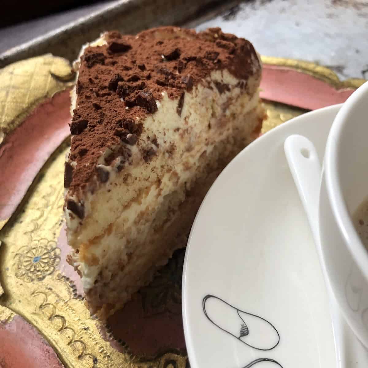 Single slice of perfect tiramisu with three creamy mascarpone and espresso soaked ladyfinger layers.
