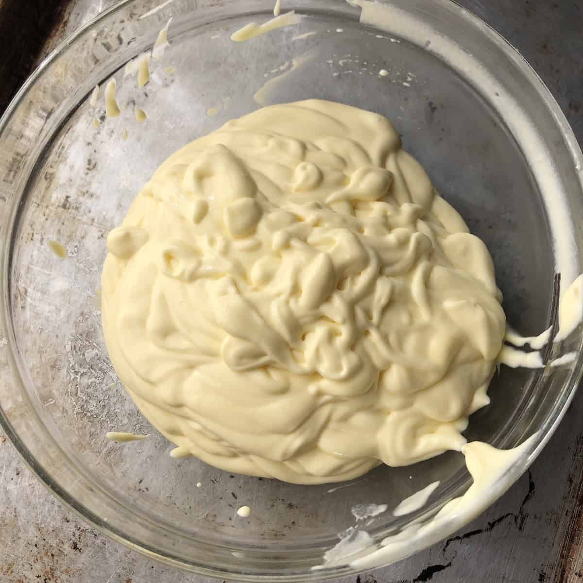 Mascarpone pate a bombe being passed through a fine mesh sieve to remove sugar shards and lumps before folding in whipped heavy cream.
