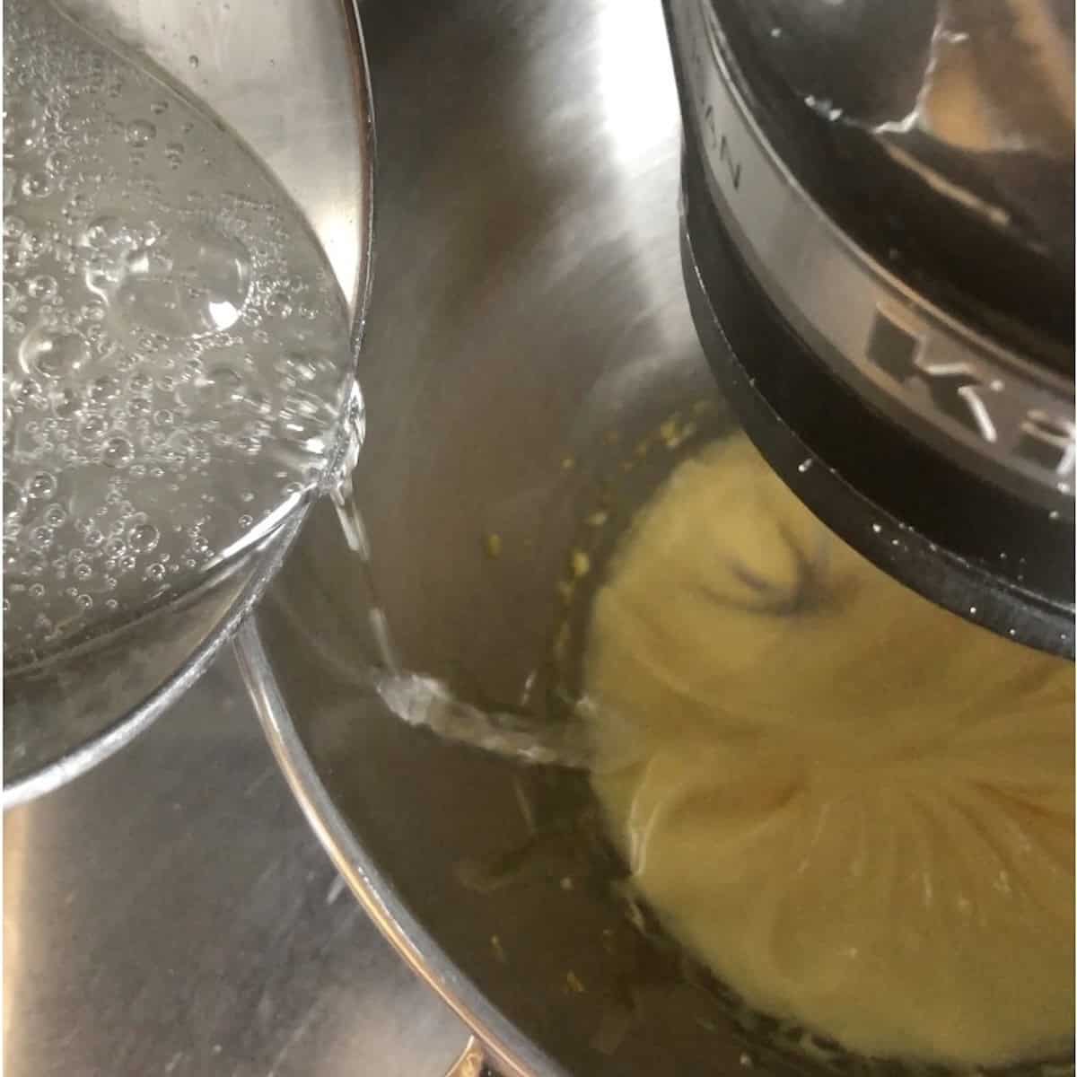 Pouring hot sugar syrup down the side of the bowl into whipped egg yolks with stand mixer running for tiramisu pate a bombe.