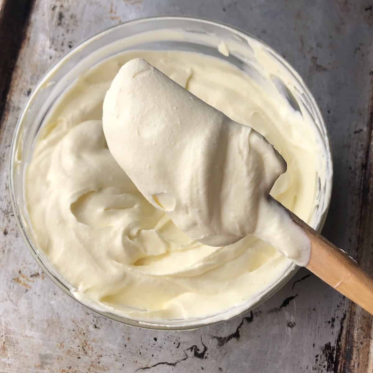 Finished tiramisu cream held up on a rubber spatula showing perfect thick consistency for layering.
