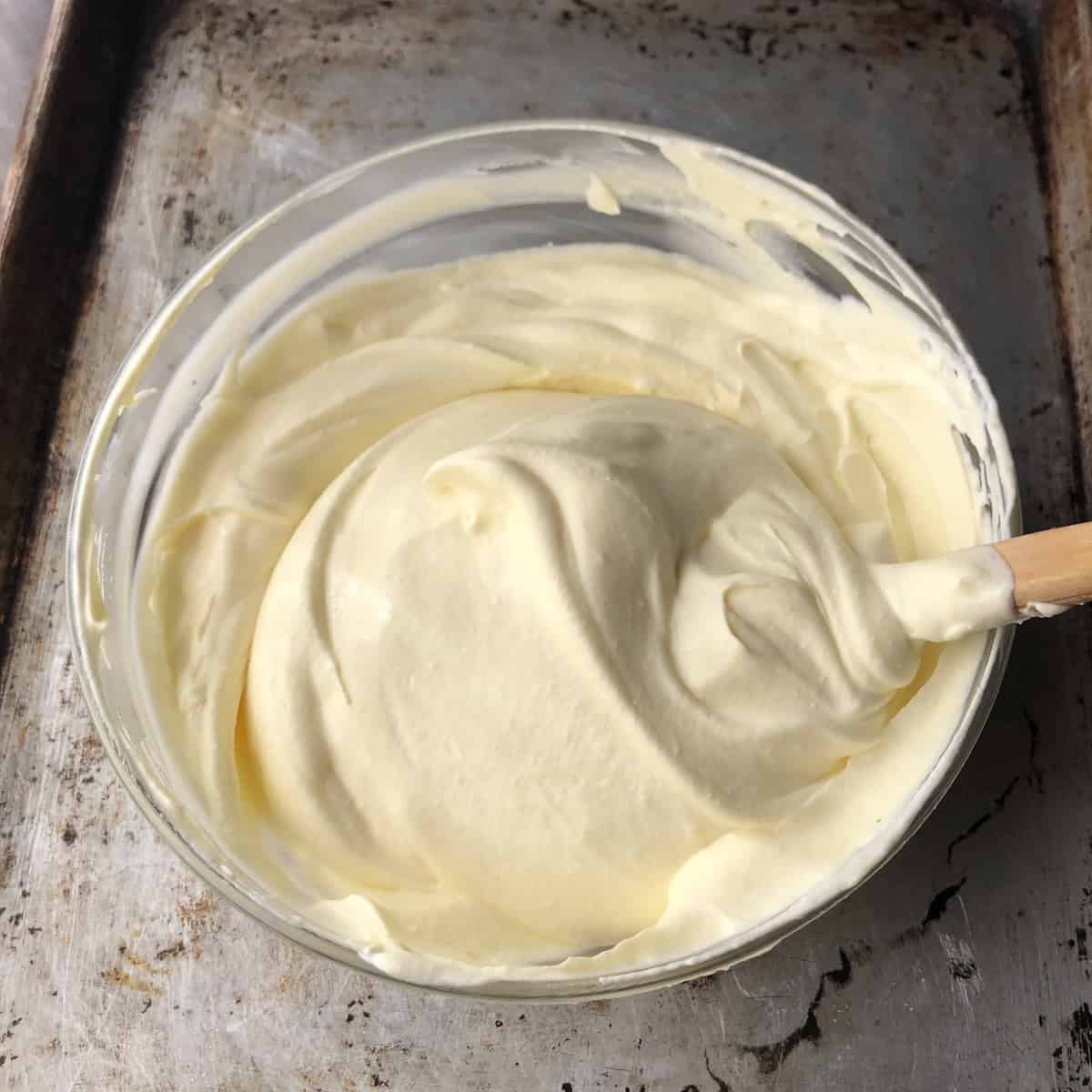 Finished tiramisu cream in a glass mixing bowl perfectly mixed, fluffy, and not runny ready to layer the dessert.
