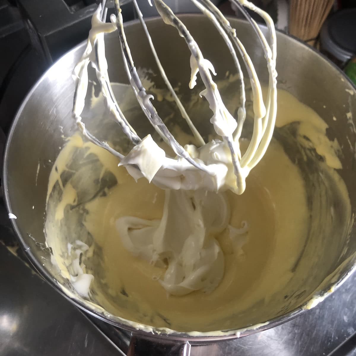 Two spoonfuls of cold mascarpone added to the whipped egg mixture to be folded in for tiramisu.