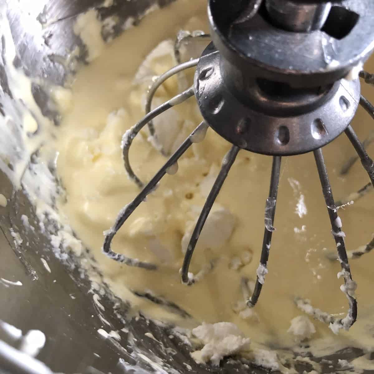 Two spoonfuls of cold mascarpone added to the whipped egg mixture to be folded in for tiramisu.