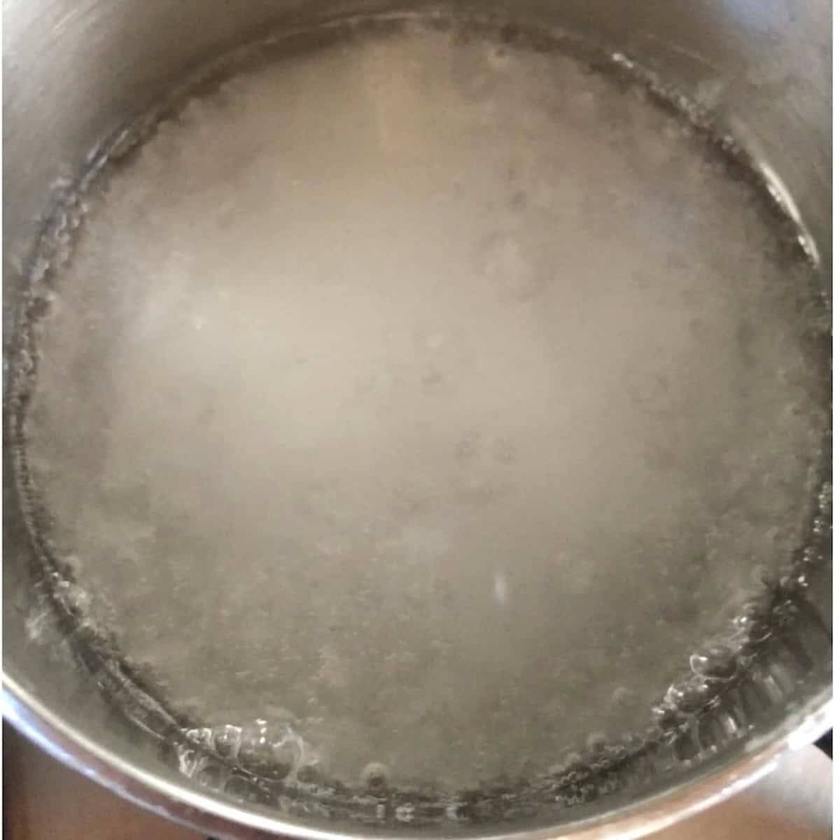 Water and sugar added to a small saucepan to make sugar syrup for pate a bombe method to pasteurize eggs in tiramisu.