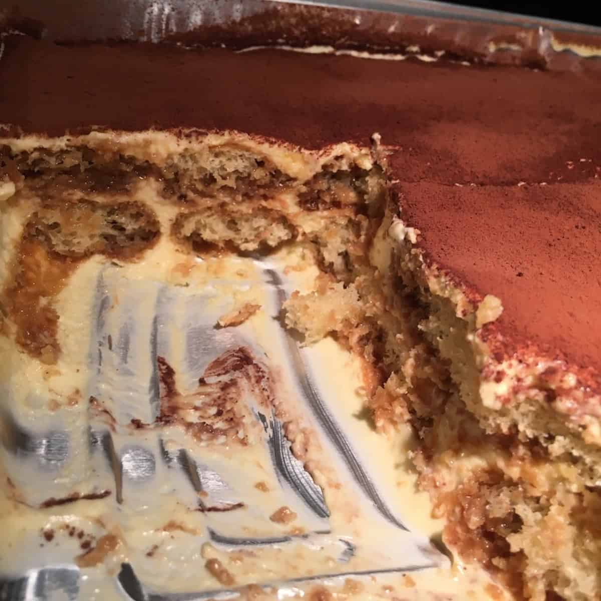 Two-layer tiramisu with scoops removed revealing perfect creamy texture and espresso soaked ladyfinger layers.

