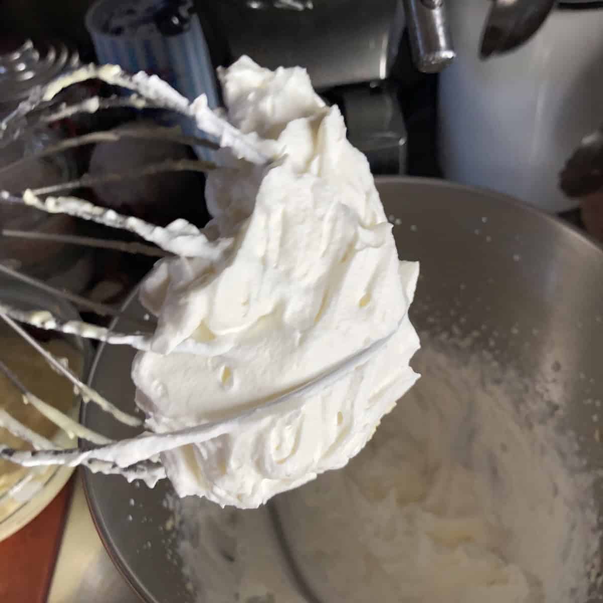 Heavy cream whipped to stiff peaks in stand mixer ready to fold into tiramisu cream.
