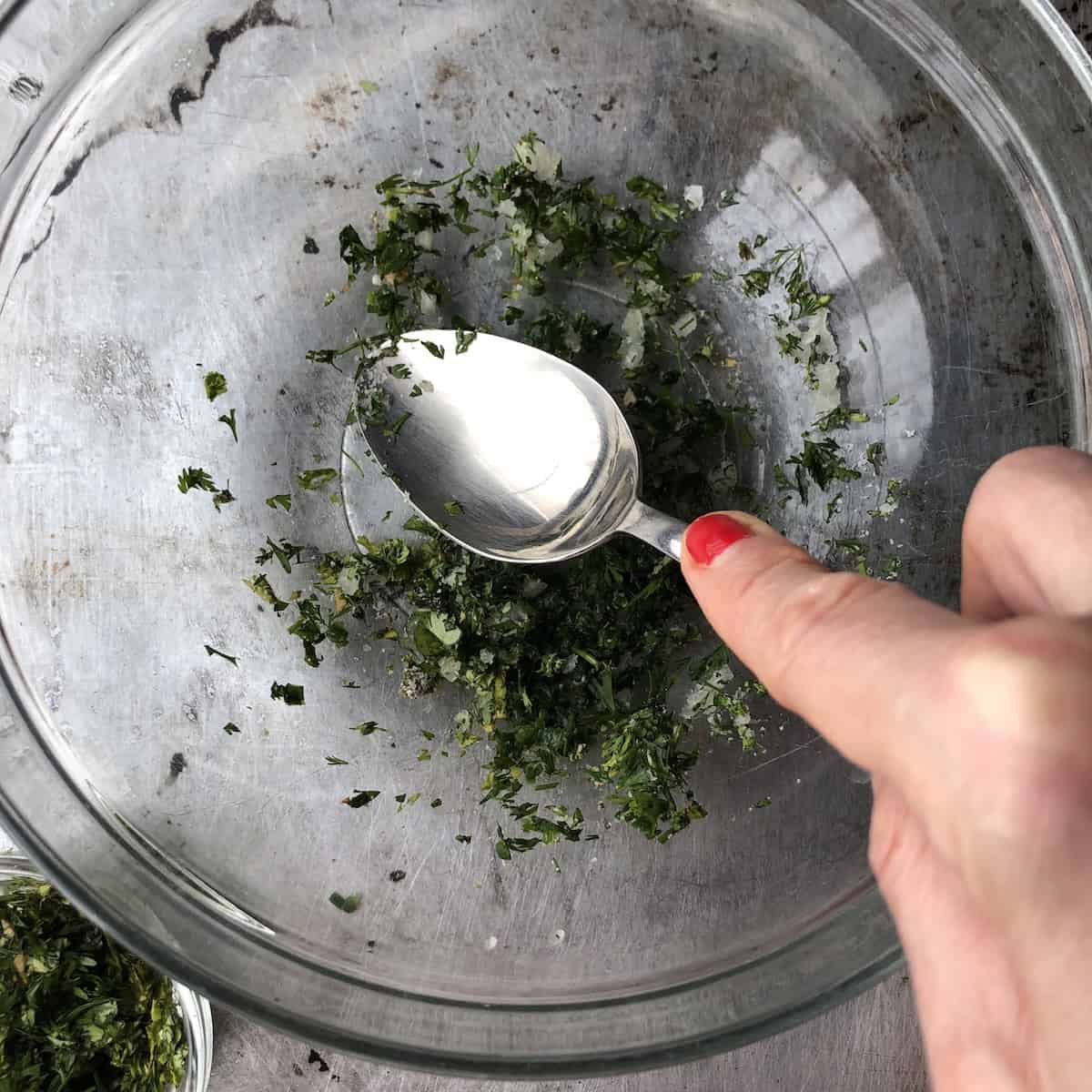 Using the back of a spoon to macerate half of the onion, jalapenos, and cilantro with kosher salt for authentic guacamole.

