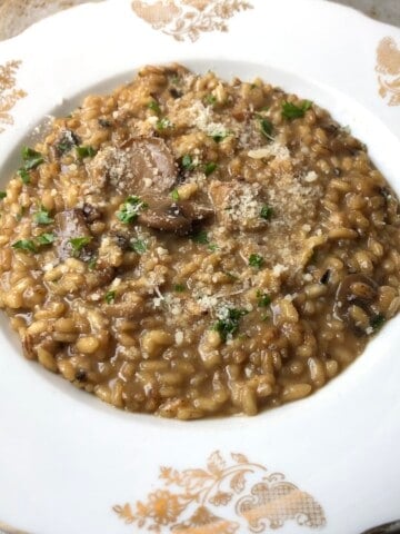 A bowl of creamy mushroom risotto garnished with minced parsley made with porcini and wild mushrooms for an easy mushroom risotto you can make at home.