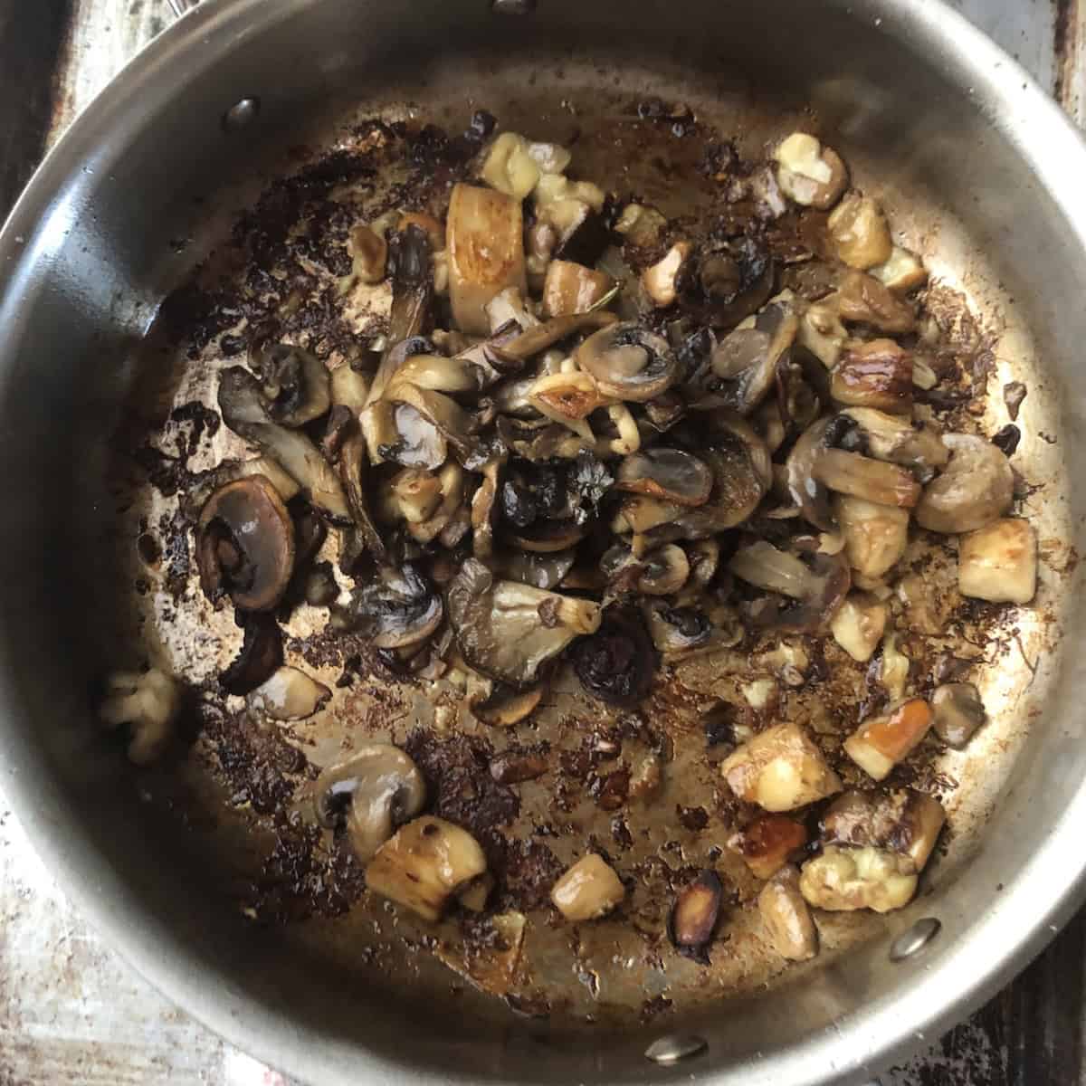Wild mushrooms added back to the saute pan with golden sauteed porcini mushrooms ready to deglaze with white wine, best mushroom risotto recipe combining fresh and porcini mushrooms.