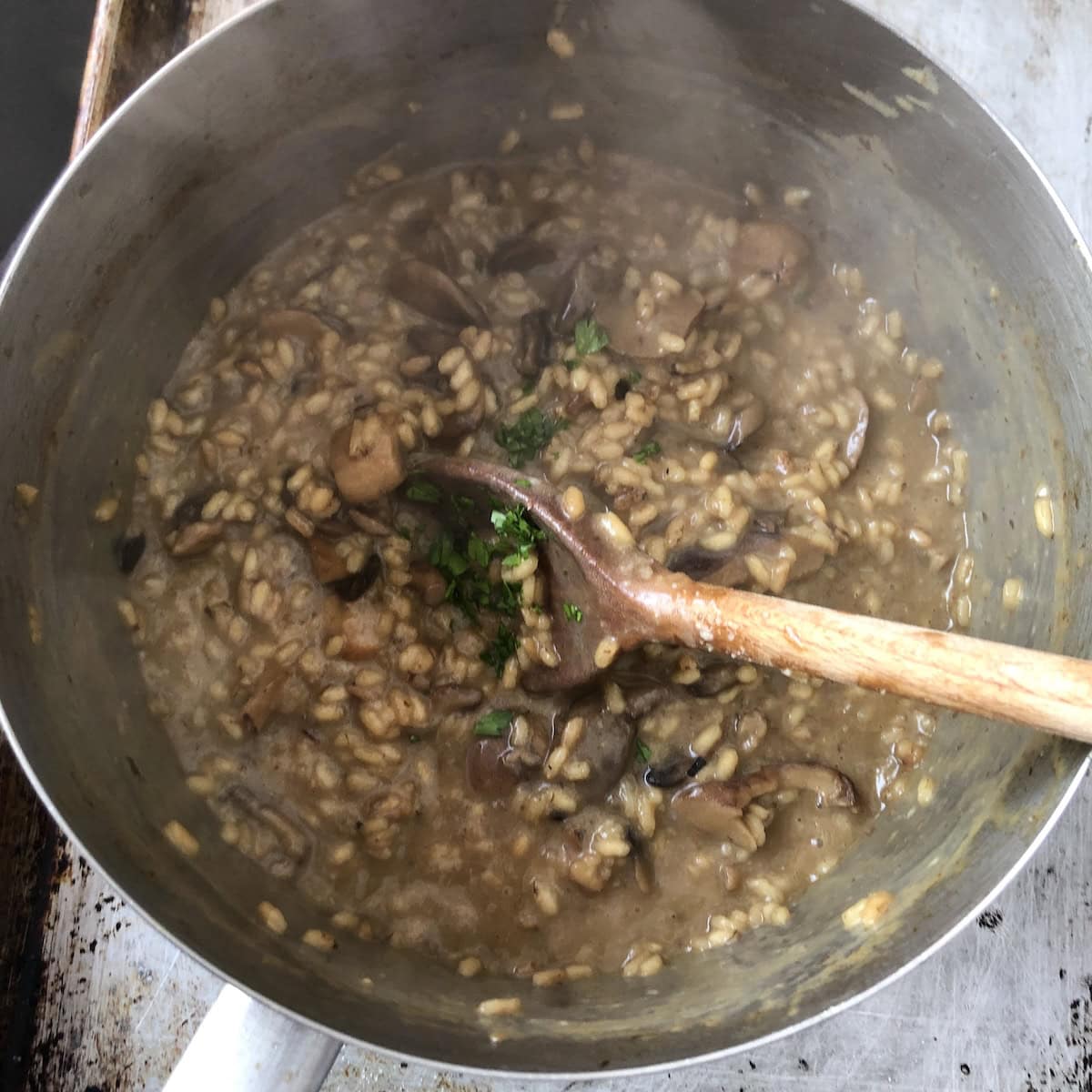 Mushroom risotto stirred together with butter, grana padano, and fresh parsley, best risotto recipe for a creamy wild mushroom and porcini risotto ready to serve.
