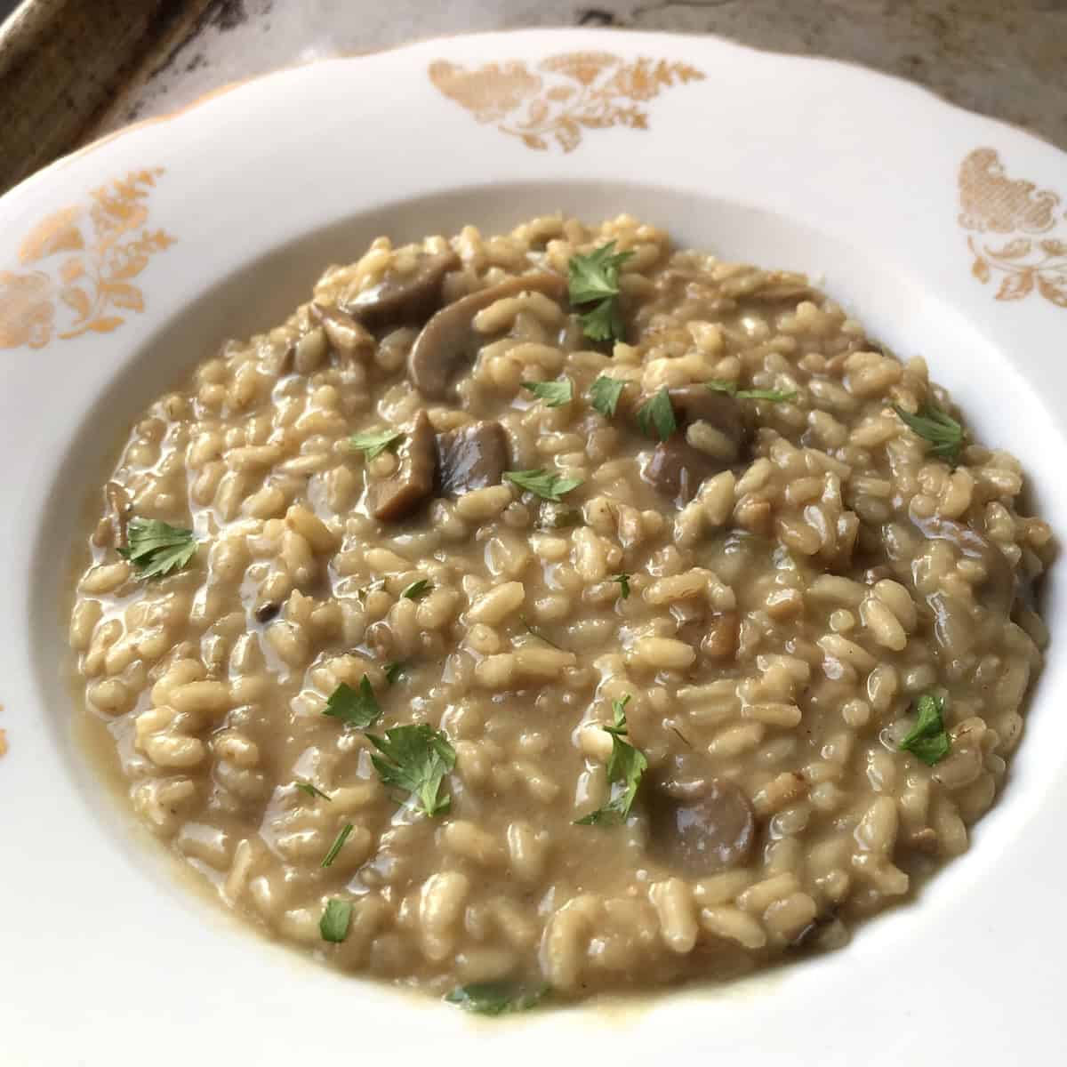A bowl of simple mushroom risotto made with champignon mushrooms for easy weeknights with optional dried porcini mushrooms for extra umami, easy risotto recipes you can make in under an hour.
