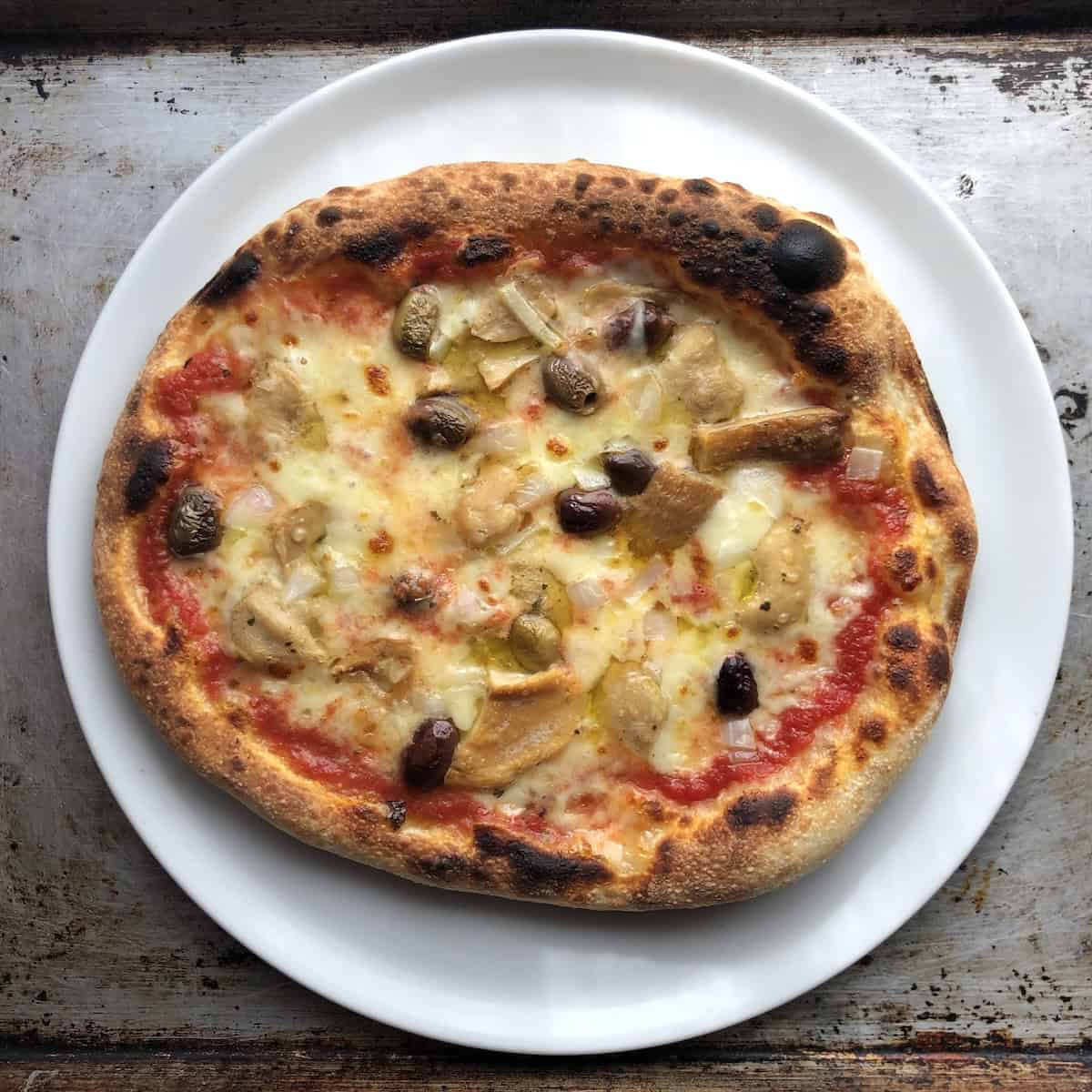 Fully baked porcini mushroom taggiasche olive and onion pizza with buffalo mozzarella on a Caputo Nuvola 00 flour thick crust pizza dough.