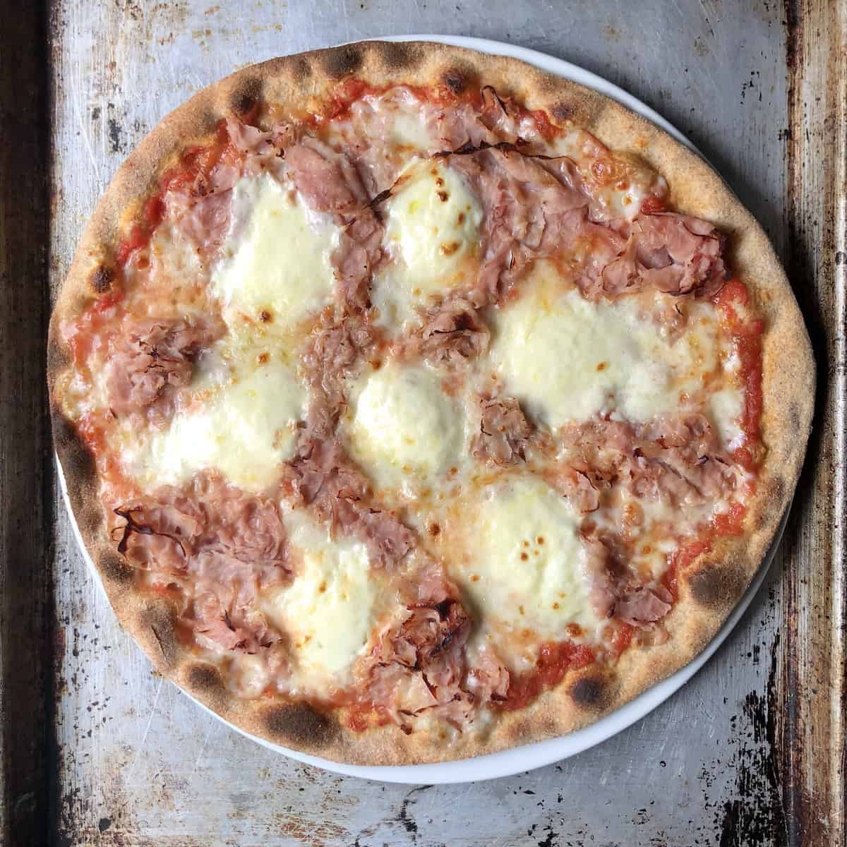 Baked homemade prosciutto and mascarpone pizza with a thinner crispier crust made with half and half dough made with bread flour and whole wheat flour pizza dough, best homemade pizza recipe version of an Italian frozen pizza classic.