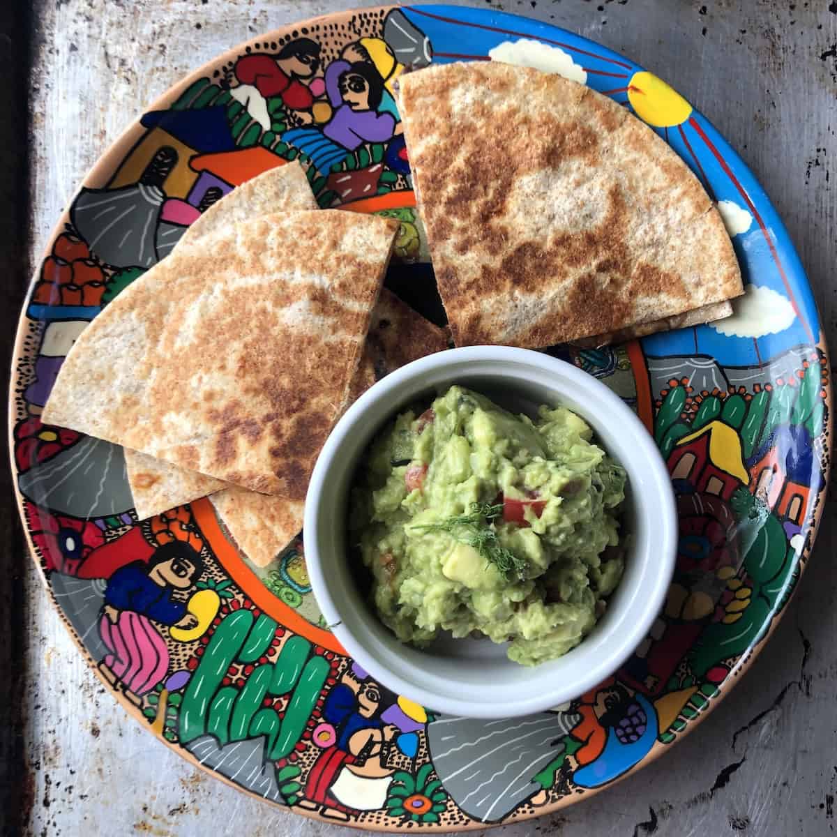 A platter of homemade black bean and cheese quesadillas platter with homemade creamy guacamole (restaurant-style Mexican recipes).
