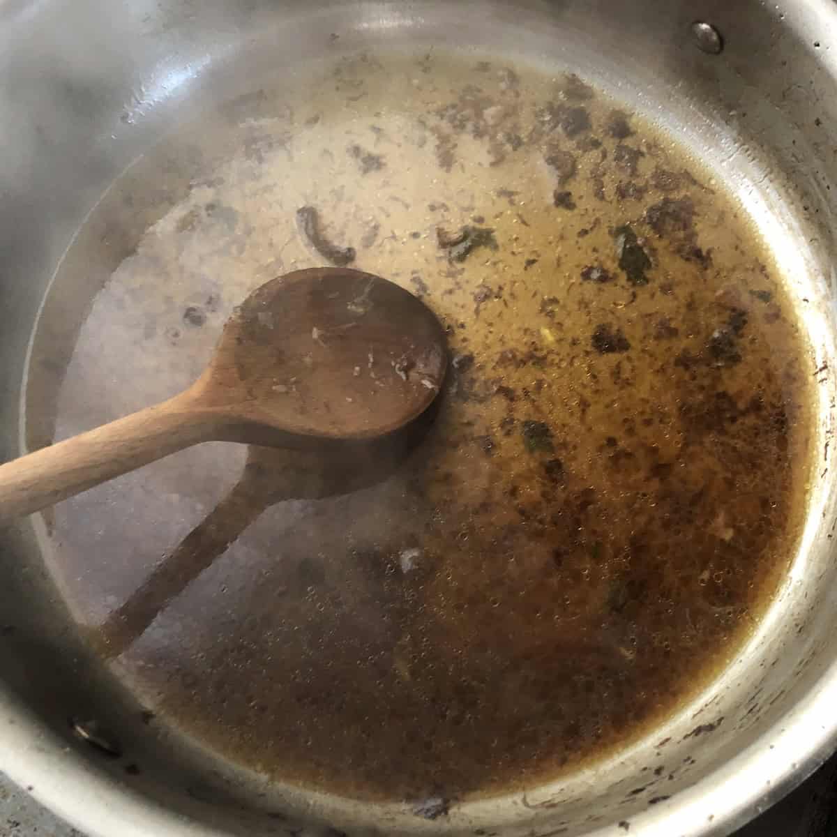 Using a wooden spoon to scrape up the remaining fond with hot broth in the saute pan, how to make risotto with deep flavor for an Italian mushroom risotto.

