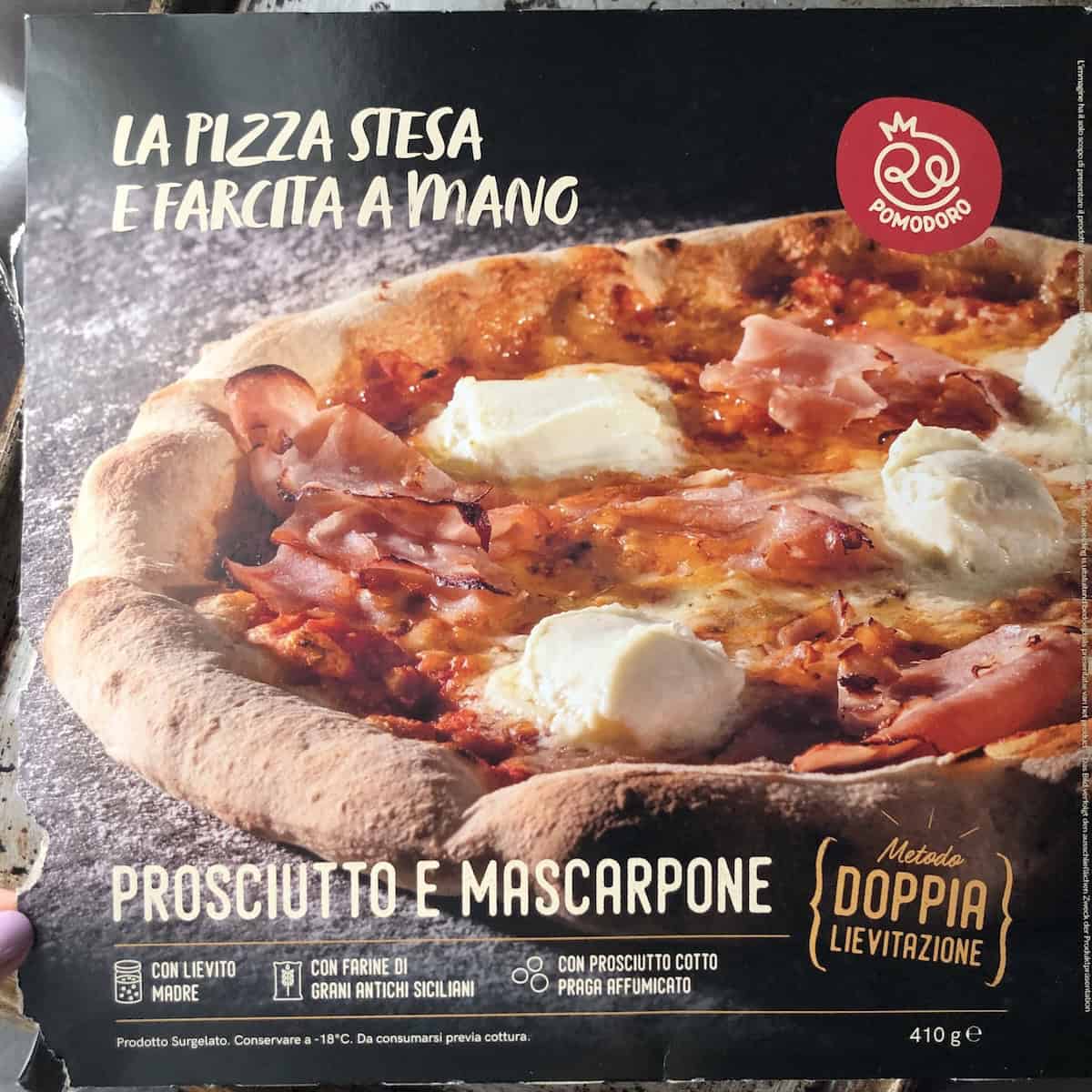 Front of an Italian artisanal frozen pizza box with handmade prosciutto praga and mascarpone from an Italian grocery store, pizza recipe inspiration for a homemade version.