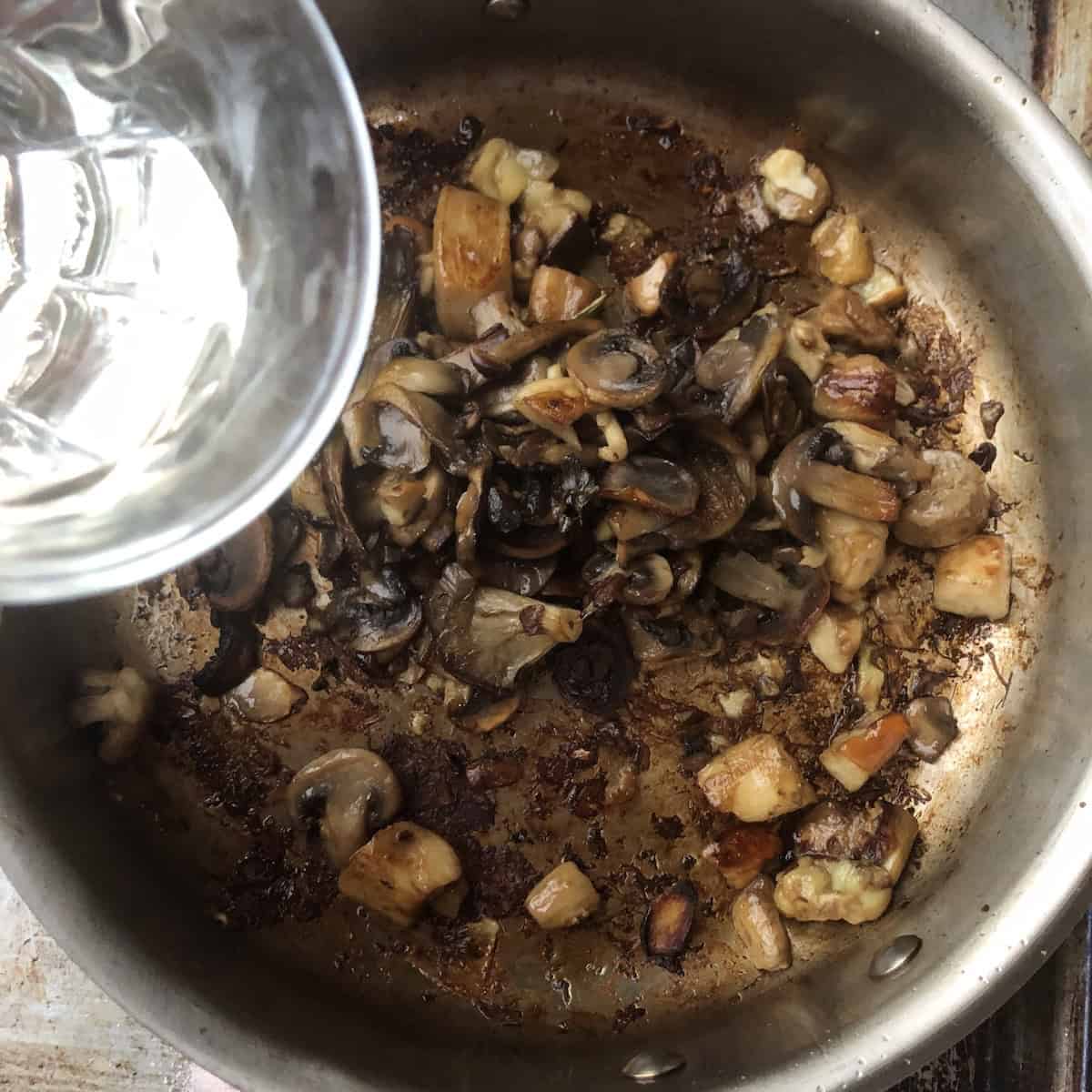 Adding white wine to deglaze the saute pan of porcini and wild mushrooms, white wine risotto technique for how to make mushroom risotto with maximum flavor.
