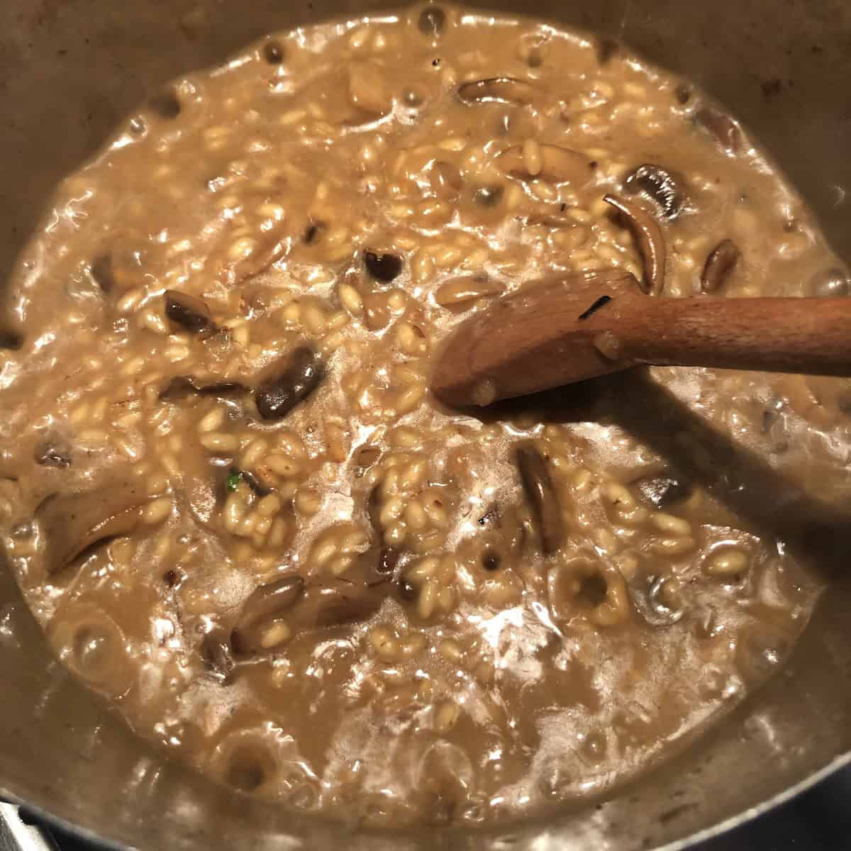 Mushroom risotto after adding all the broth needed cooked to al dente and ready to rest for one minute off the heat, perfect risotto consistency for a creamy mushroom risotto recipe.

