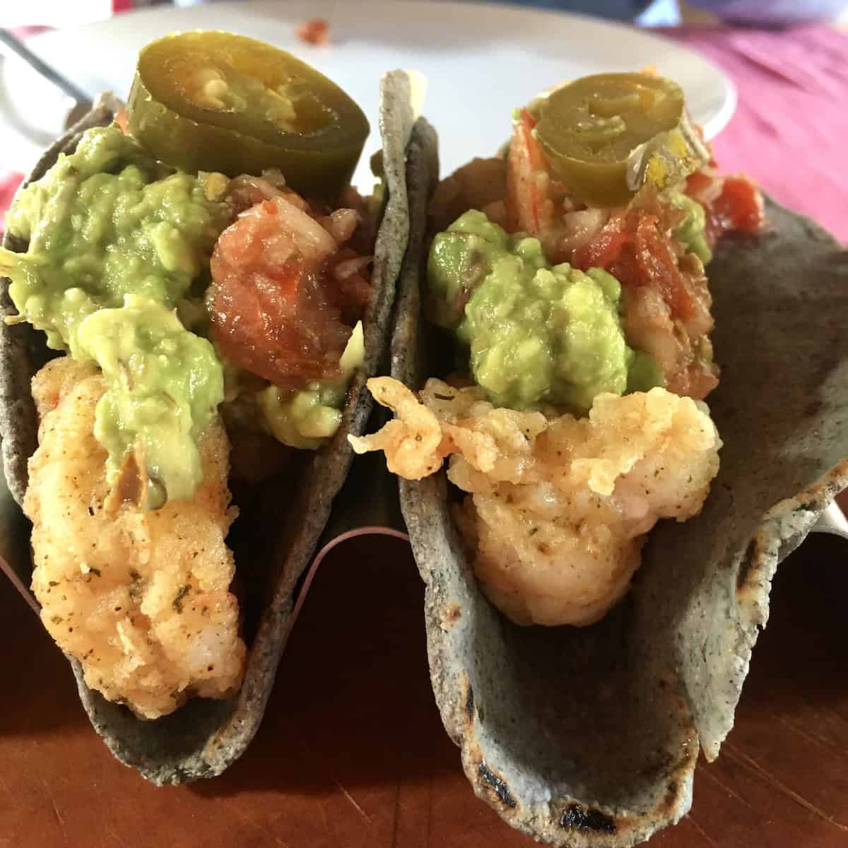 Fried shrimp tacos with salsa and homemade guacamole in homemade blue corn tortillas.
