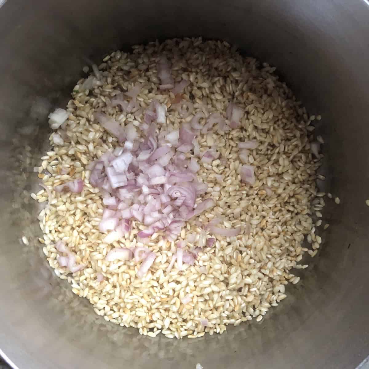 Golden toasted risotto rice with diced shallots added to cook until translucent, risotto ingredients coming together for a creamy mushroom risotto from scratch.

