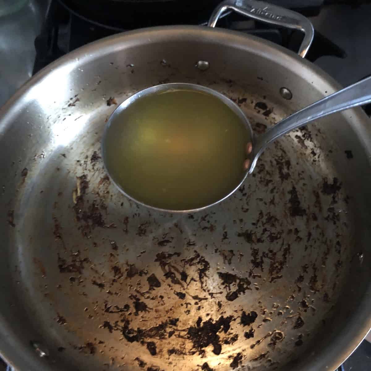 Adding a ladle of hot broth to the saute pan to pick up remaining flavor from the deglazed mushrooms, risotto recipe technique for maximum flavor in a mushroom risotto.
