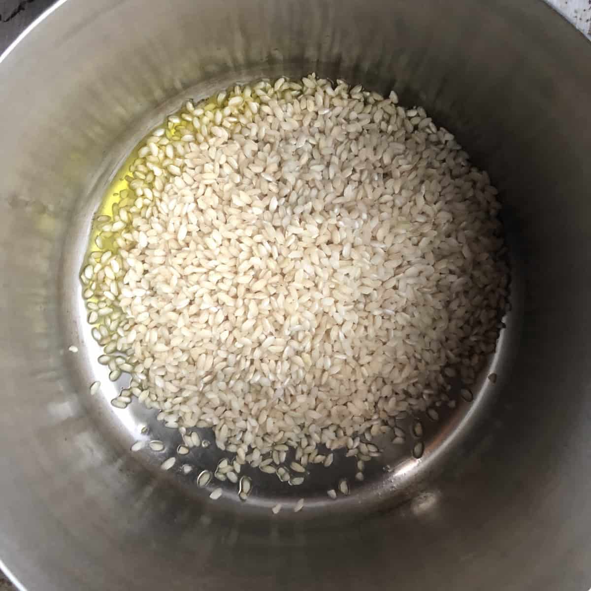Risotto rice added to a pot with olive oil for the tostatura toasting step, rice for risotto technique that builds a nutty base for the best risotto recipe.
