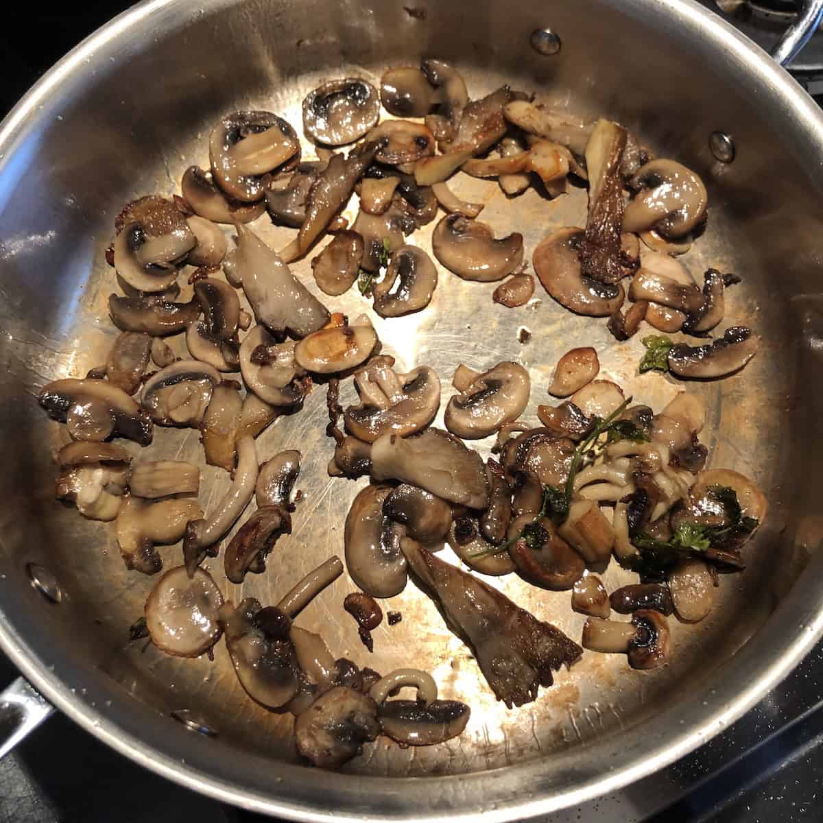 Fully browned wild mushrooms in a saute pan for a mushroom risotto recipe, perfectly sauteed mushrooms ready to set aside for a gourmet mushroom risotto.
