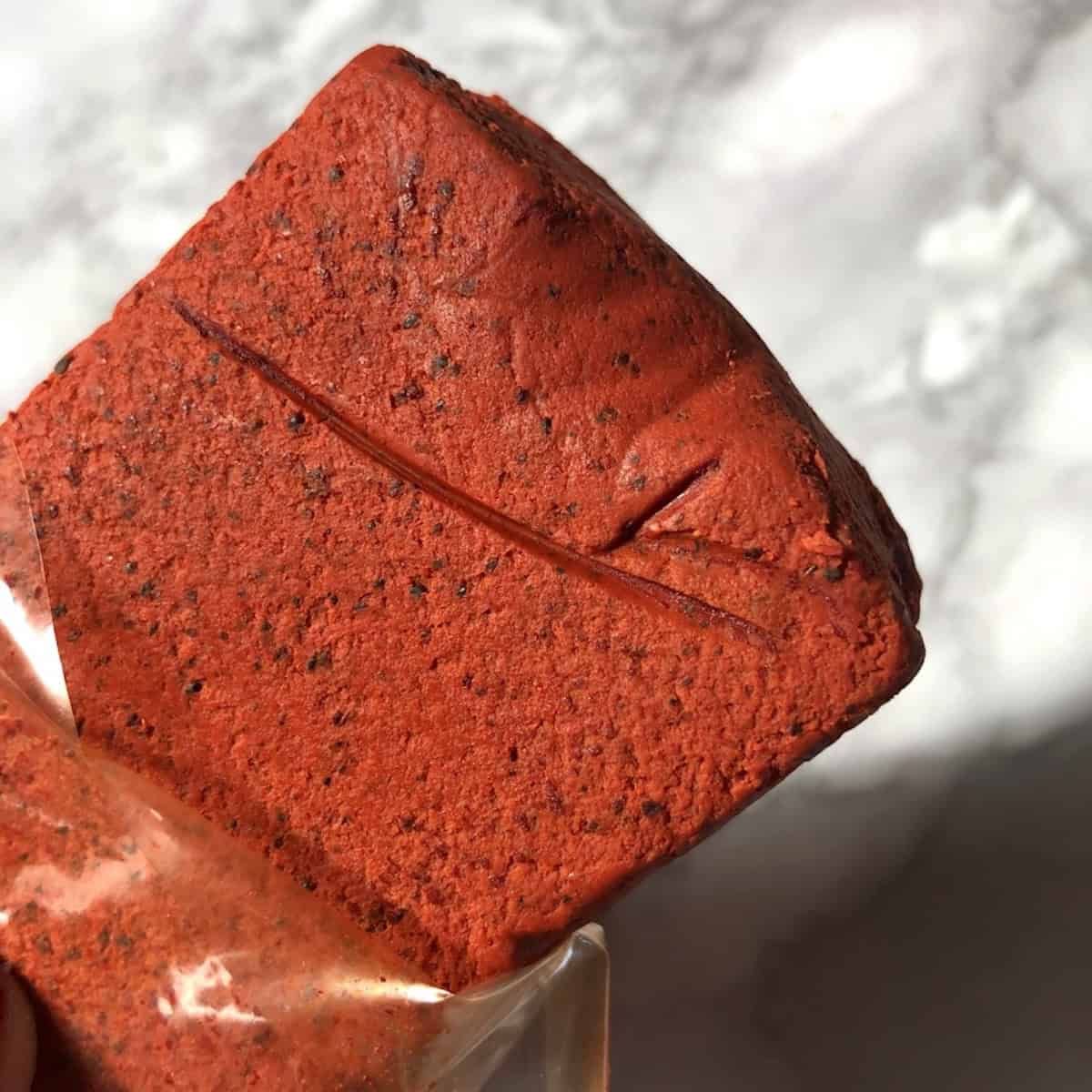 A brick of bright orange-red achiote paste used as an achiote seasoning ingredient for pollo asado marinade recipe.