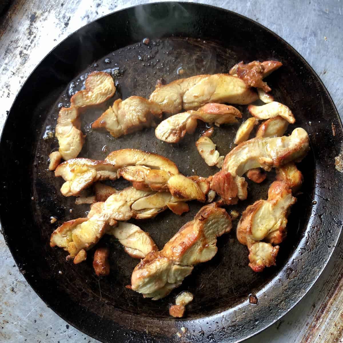 Fully reheated pollo asado chicken slices still juicy in a cast iron pan, pollos al carbon ready to use in tacos, enchiladas, salads, quesadillas, or fajitas. or to make mexican shredded chicken for flautas or taquitos.
