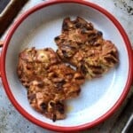 Grilled pollo asado skinless boneless chicken thighs with grill marks on a round serving platter, pollo asado recipe.