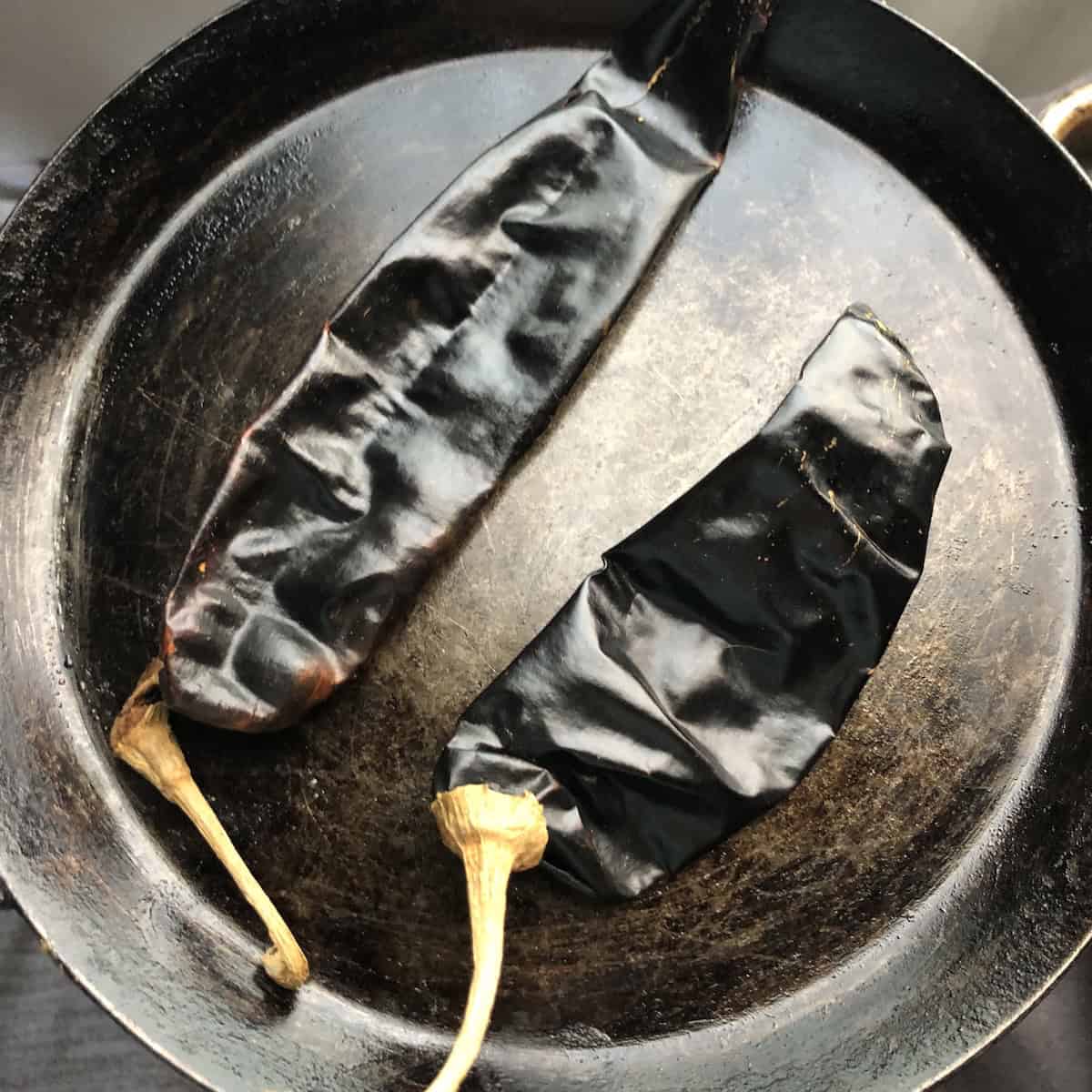 Guajillo chiles in a seasoned De Buyer crepe pan ready to be toasted for authentic chicken tortilla soup.

