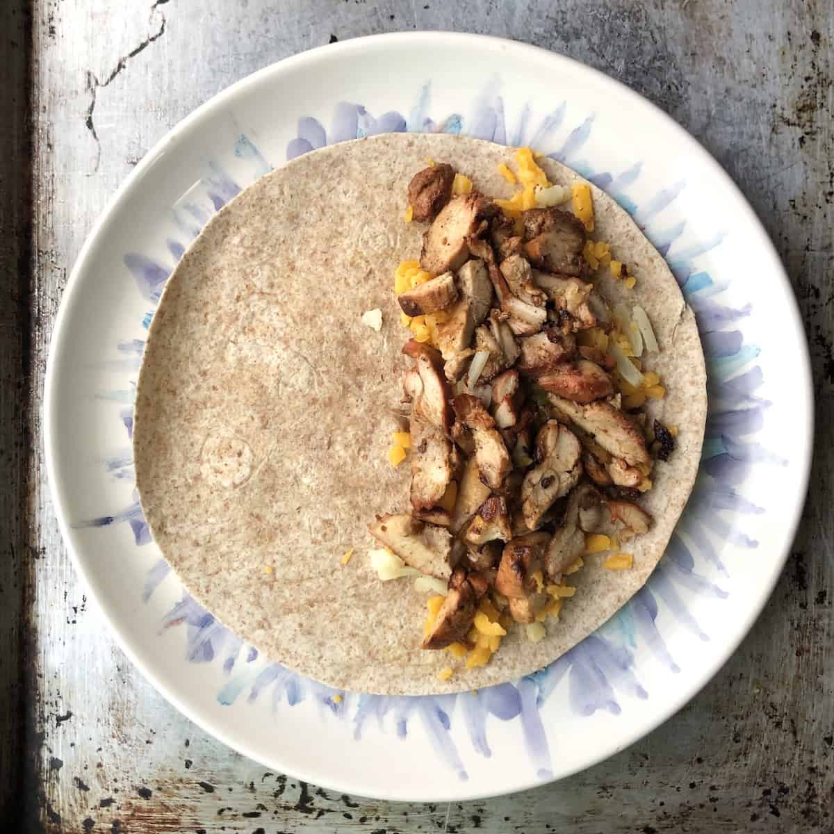 Sliced pollo asado chicken added on top of the cheese layer on the tortilla for chicken quesadilla recipes.
