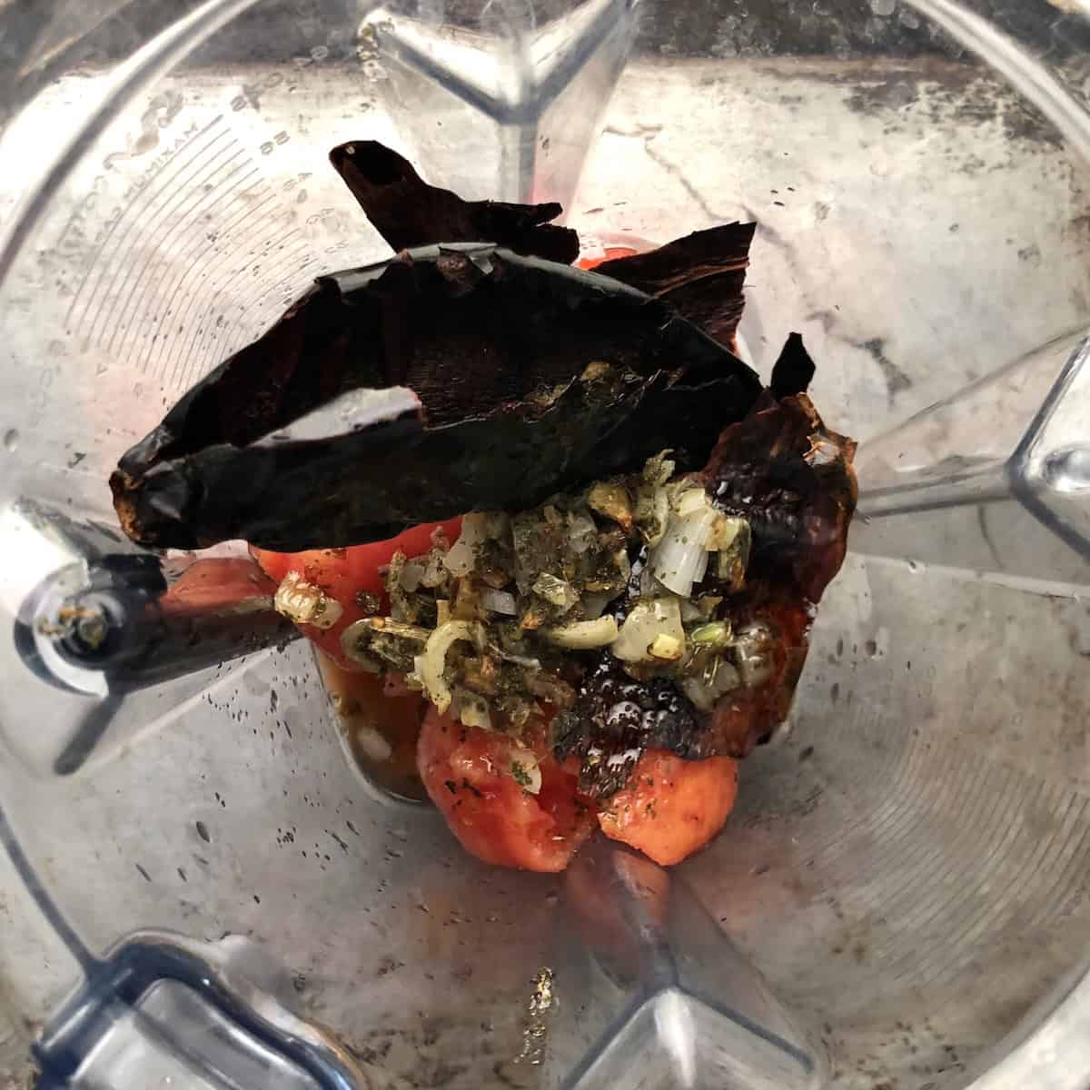 Fire-roasted tomatoes, toasted guajillo chiles, and sauteed onions, garlic, and epazote in a Vitamix blender ready to blend.

