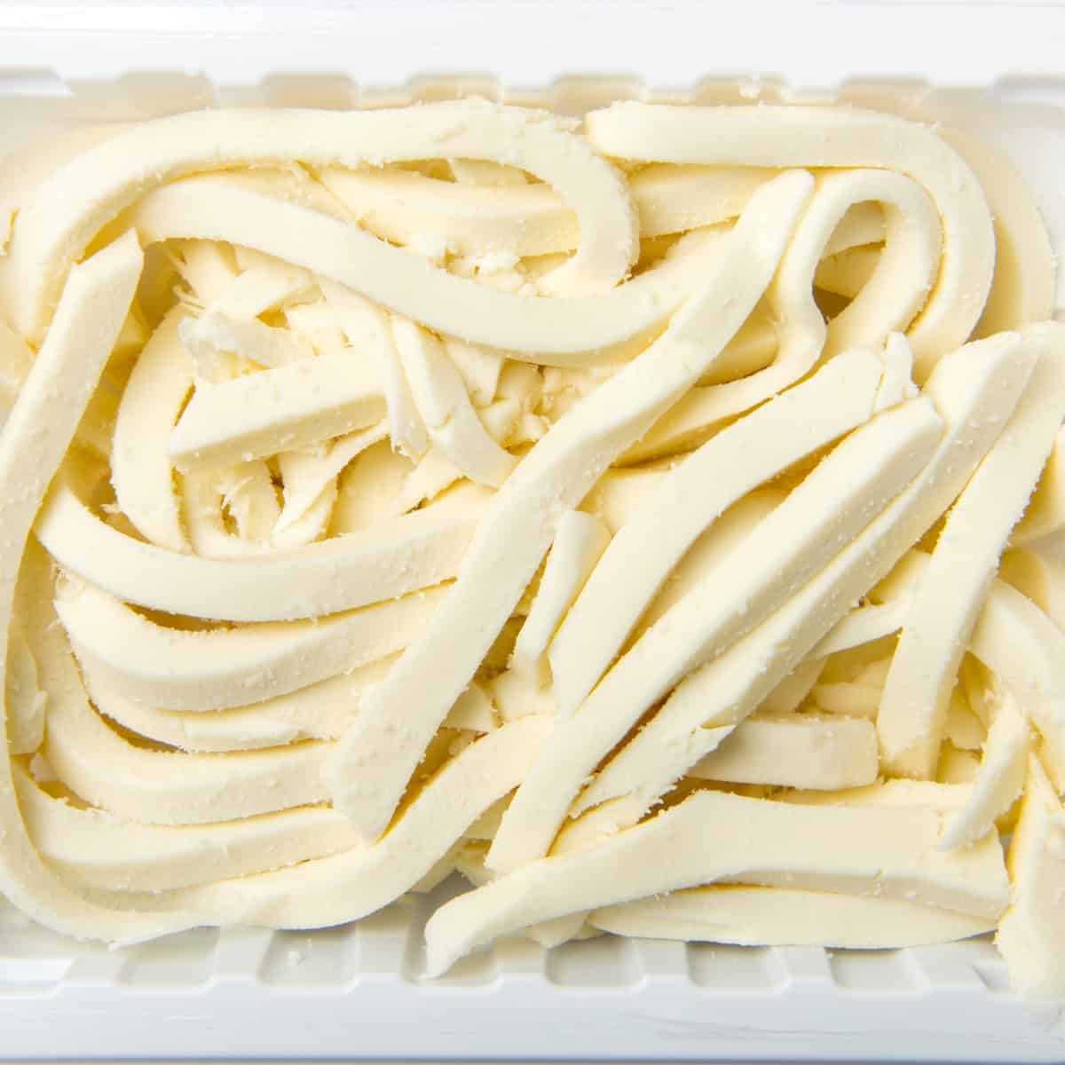 A container of fresh Oaxaca cheese for homemade chicken quesadillas.
