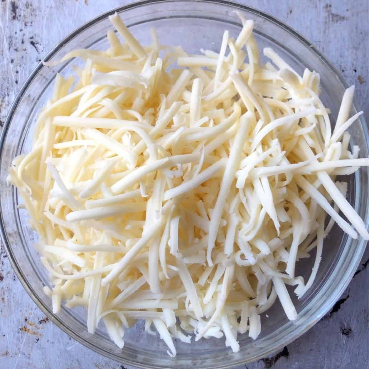 A bowl of freshly grated monterey jack cheese for a chicken quesadilla recipe.
