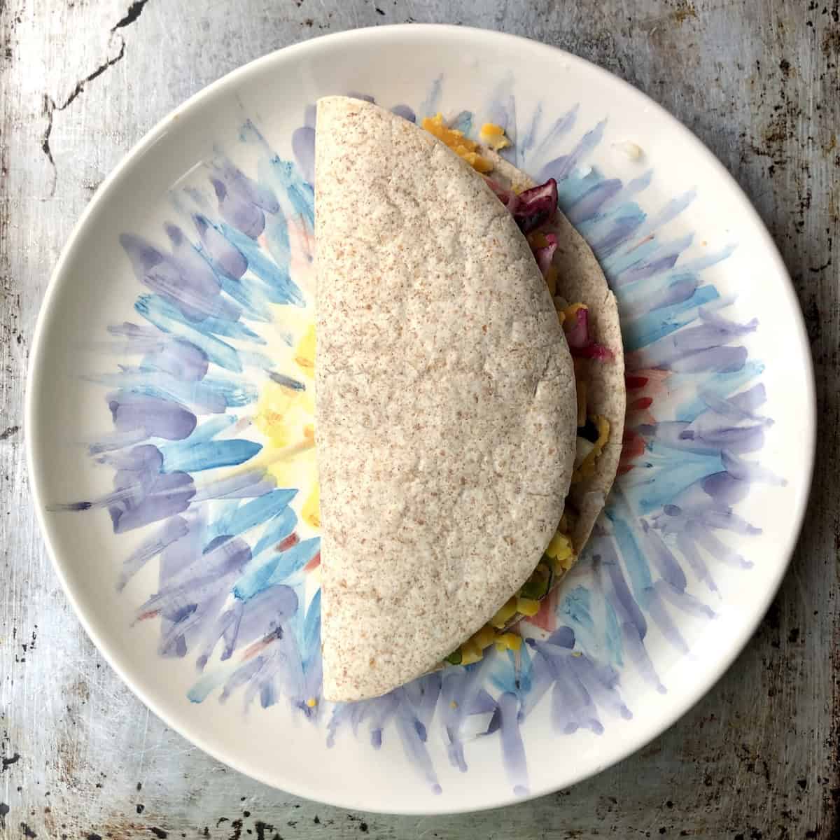 The tortilla folded over the fillings showing how to make quesadillas with chicken, ready to cook.
