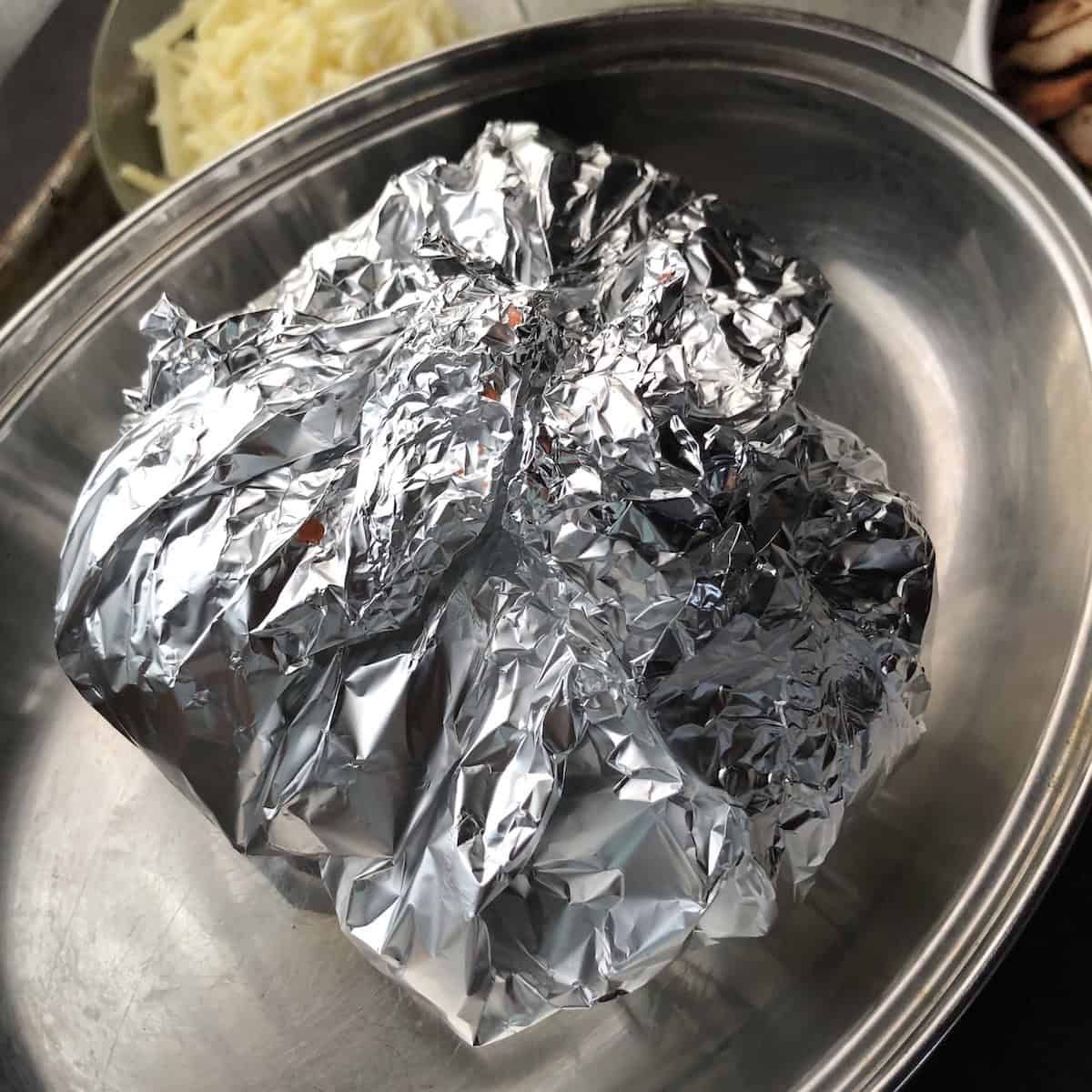 Fire-roasted tomatoes wrapped in aluminum foil to steam so the peels can be removed easily for mexican tortilla soup.
