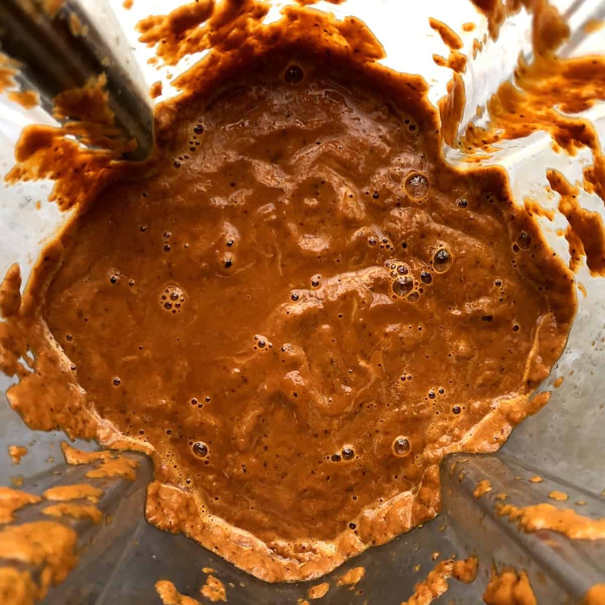 Smooth bright orange-red puree of fire-roasted tomatoes, guajillo chiles, and aromatics blended in a Vitamix for mexican tortilla soup recipe.
