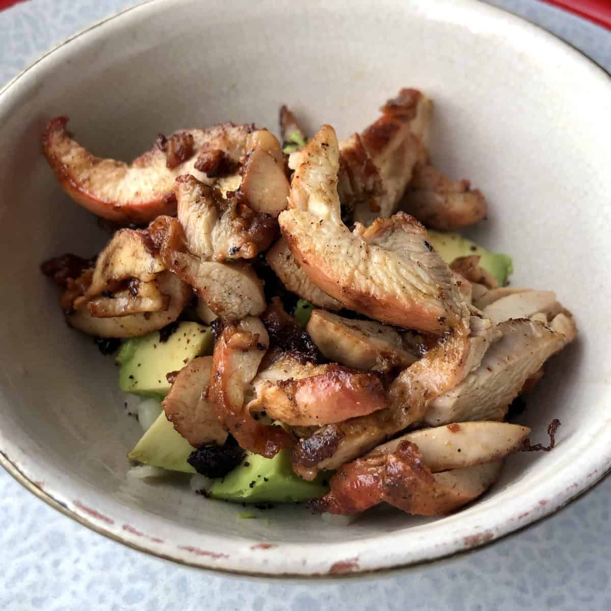 Sliced pollo asado chicken added to the garnished bowl for chicken tortilla soup.