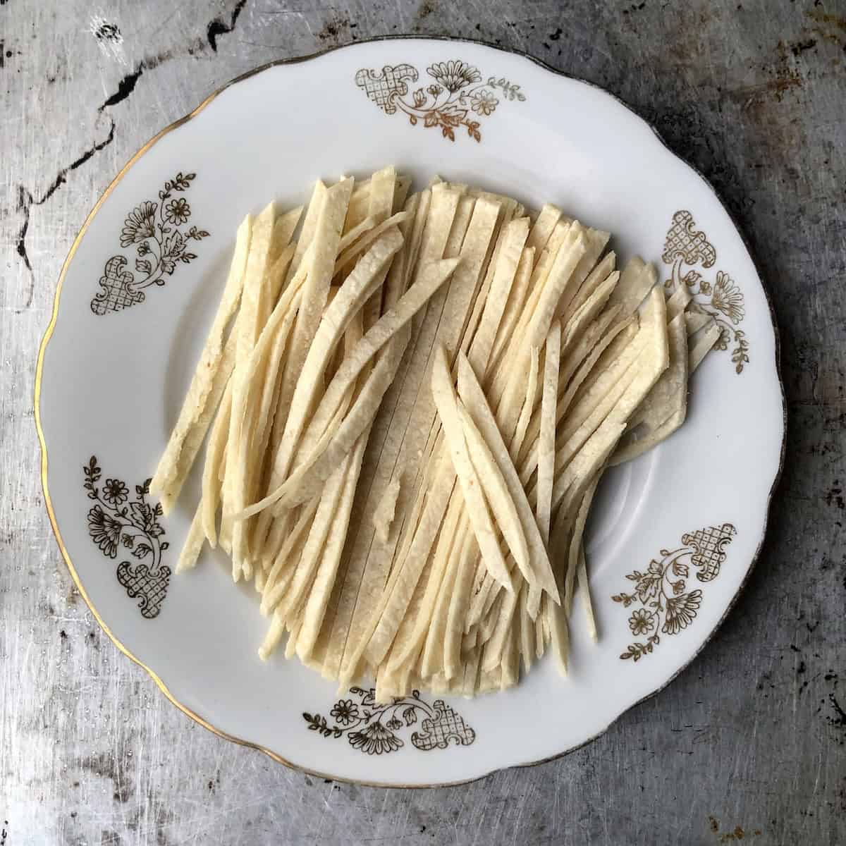 A stack of corn tortillas cut into quarter-inch strips ready to be fried for tortilla soup.
