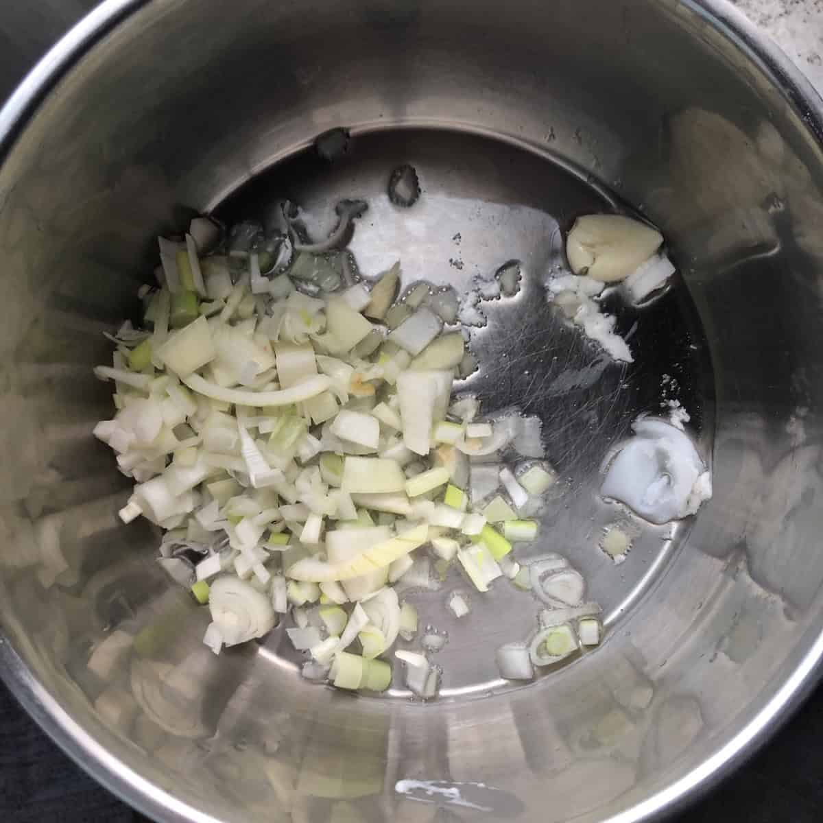 Lard, diced onions, and garlic seasoned with salt cooking in a saucepan before adding the dried epazote. 
