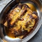 Three baked cheesy chicken enchiladas with melted cheese, a red oil slick, and crispy tortilla edges.