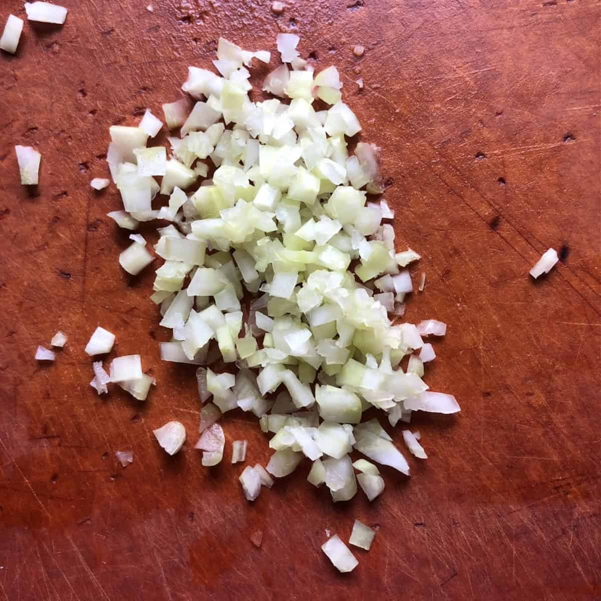 Finely diced white onions on a cutting board ready for the chicken enchilada filling. 